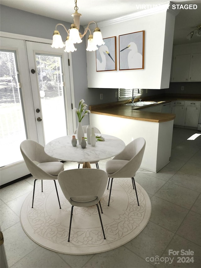 tiled dining area with a notable chandelier, crown molding, and sink