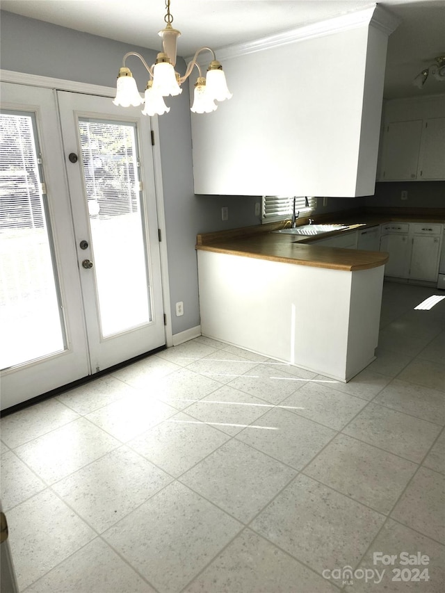 kitchen featuring an inviting chandelier, crown molding, sink, hanging light fixtures, and light tile patterned floors