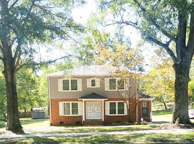 colonial house with entry steps, crawl space, brick siding, and a front yard