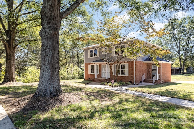 colonial inspired home featuring crawl space, entry steps, a front yard, and brick siding