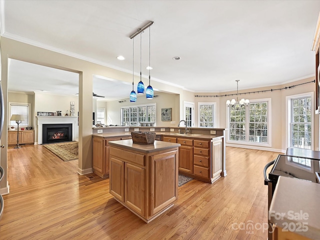 kitchen with hanging light fixtures, light wood-type flooring, kitchen peninsula, and a center island