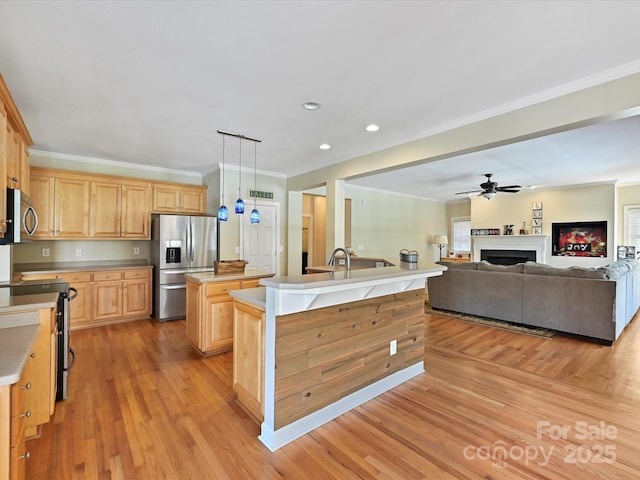 kitchen featuring appliances with stainless steel finishes, pendant lighting, a center island with sink, and light wood-type flooring