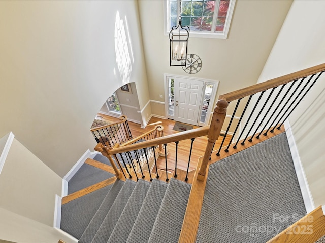 staircase featuring a towering ceiling, a chandelier, and hardwood / wood-style floors