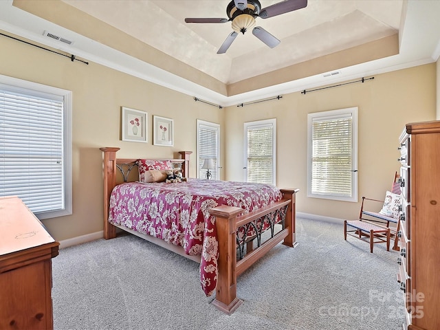 bedroom featuring light carpet, a raised ceiling, and ceiling fan