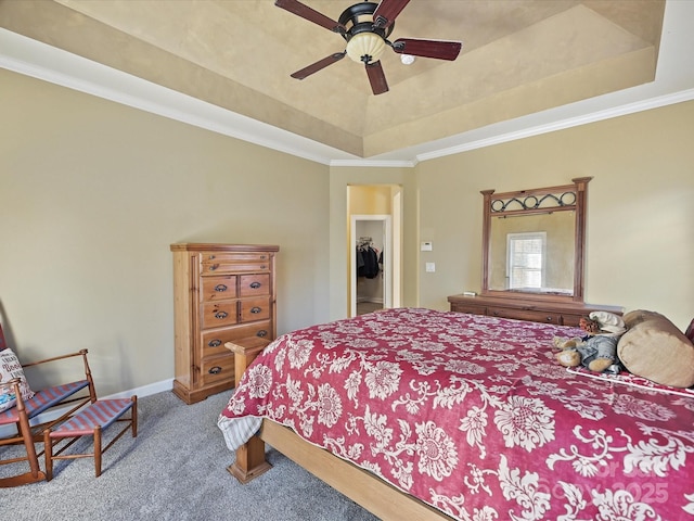 carpeted bedroom with a tray ceiling, ornamental molding, and ceiling fan