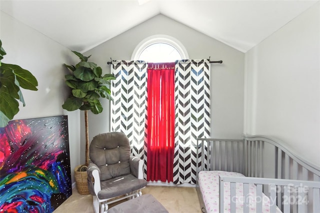 bedroom with a nursery area, vaulted ceiling, and light carpet