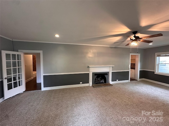 unfurnished living room featuring a fireplace with raised hearth, recessed lighting, carpet flooring, crown molding, and baseboards