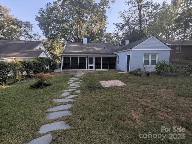 rear view of property with stucco siding, a lawn, and a sunroom