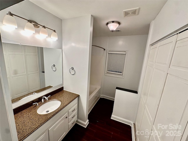 full bath with vanity, washtub / shower combination, wood finished floors, and visible vents