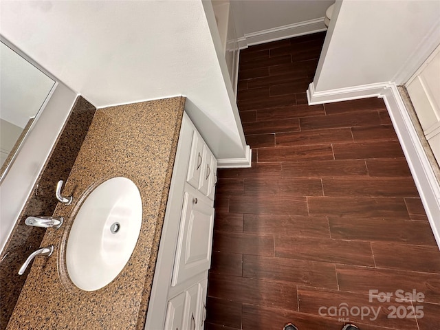 full bath featuring a sink, baseboards, and wood finish floors