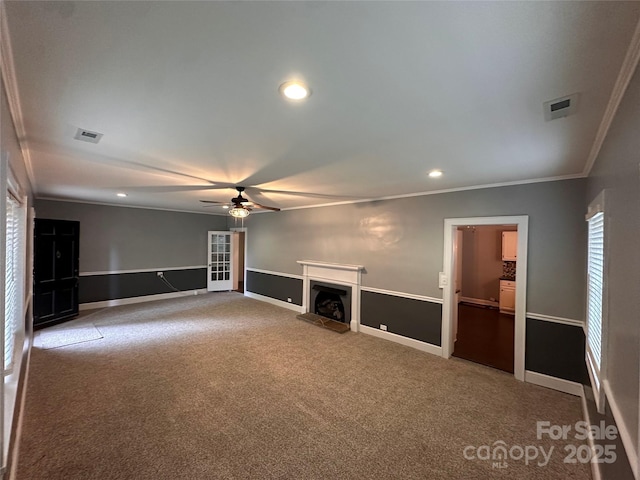 unfurnished living room featuring visible vents, a fireplace with raised hearth, crown molding, carpet flooring, and recessed lighting