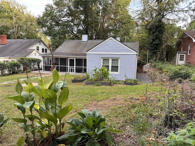 back of property with a yard, a sunroom, and a chimney