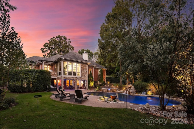 back house at dusk featuring a patio and a yard