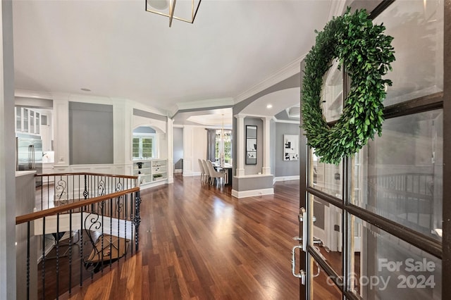 entryway with crown molding, decorative columns, dark hardwood / wood-style floors, and a chandelier