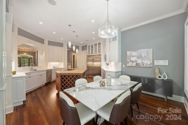 dining room with radiator, sink, dark wood-type flooring, a chandelier, and crown molding