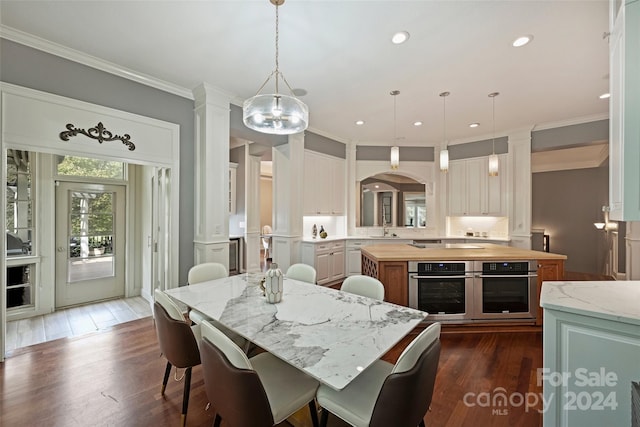 dining area with dark wood-type flooring, ornate columns, crown molding, sink, and a chandelier