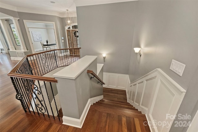 stairs with hardwood / wood-style flooring, ornamental molding, an inviting chandelier, and ornate columns