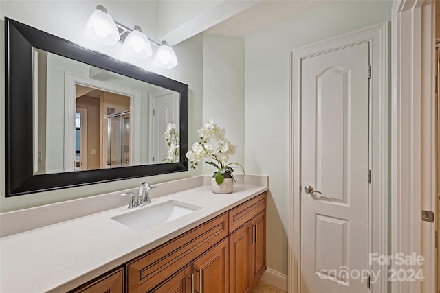 bathroom with a shower with shower door and vanity