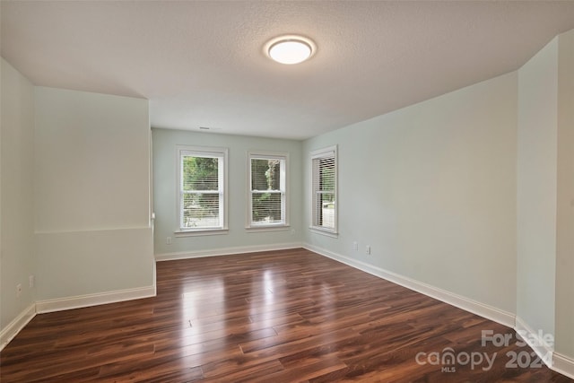 empty room with a textured ceiling and dark hardwood / wood-style flooring