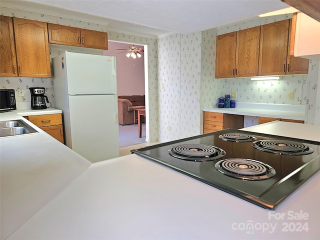 kitchen featuring white refrigerator, sink, black range, crown molding, and ceiling fan