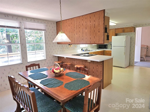 kitchen with a textured ceiling, sink, kitchen peninsula, hanging light fixtures, and black appliances