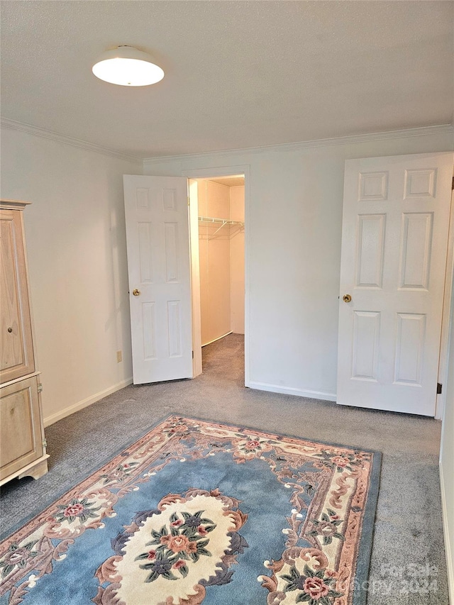 unfurnished bedroom with carpet, crown molding, a walk in closet, and a closet