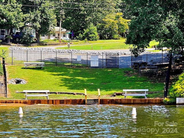 surrounding community with a water view and a yard