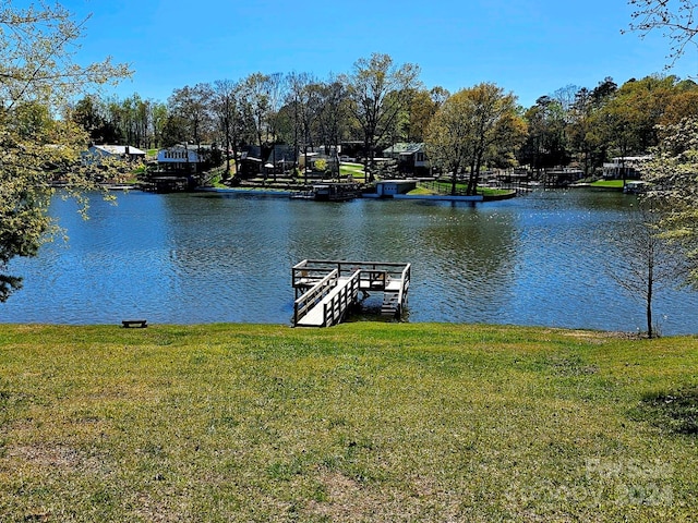 view of dock with a lawn and a water view