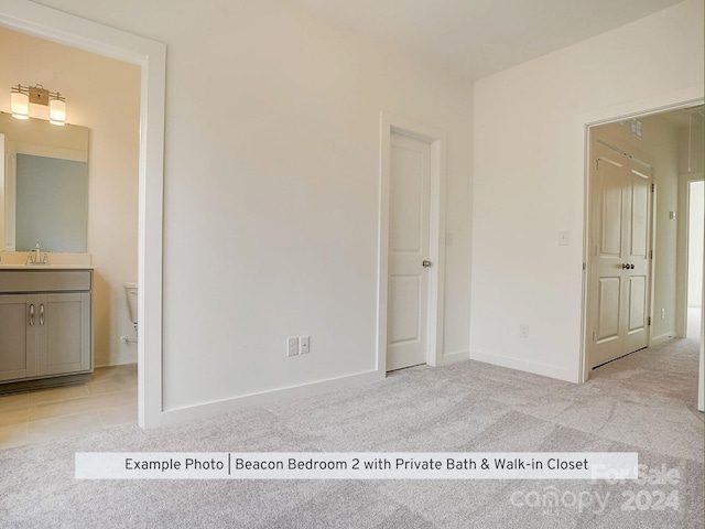 unfurnished bedroom with connected bathroom, light colored carpet, and sink