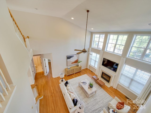 living room with light hardwood / wood-style flooring, high vaulted ceiling, and ceiling fan