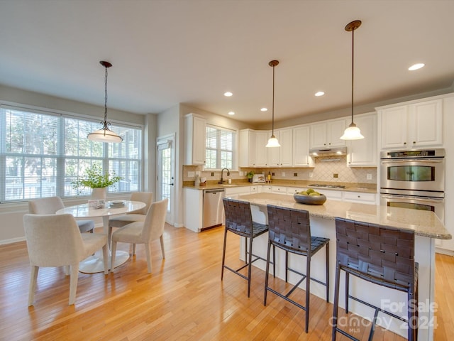 kitchen with light hardwood / wood-style floors, white cabinets, appliances with stainless steel finishes, and a kitchen island