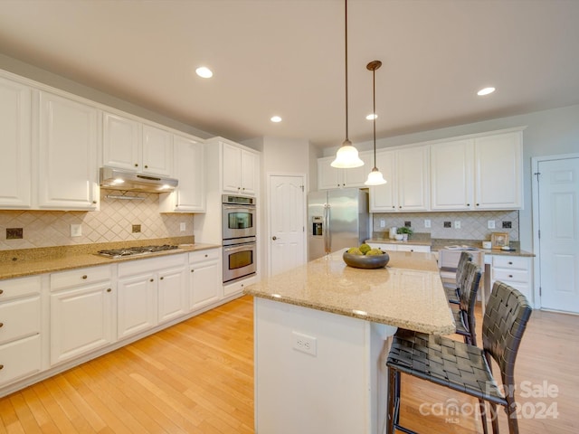 kitchen with appliances with stainless steel finishes, light hardwood / wood-style flooring, white cabinetry, and decorative light fixtures