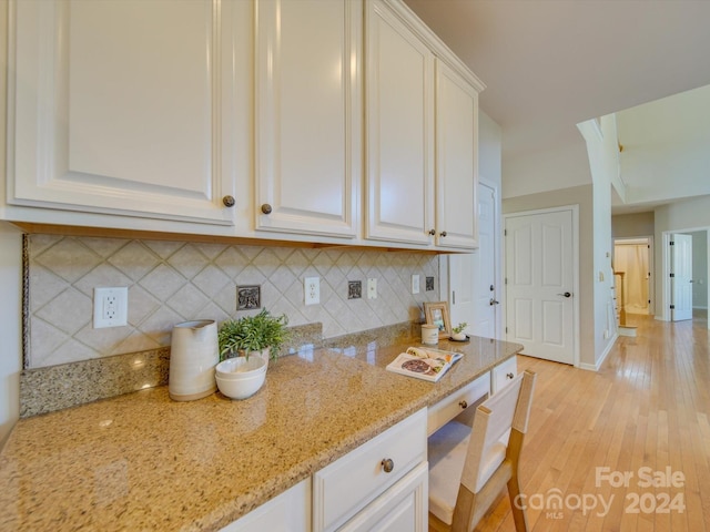 kitchen with light hardwood / wood-style floors, decorative backsplash, white cabinetry, and light stone counters