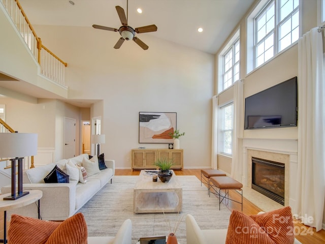 living room featuring light hardwood / wood-style flooring, high vaulted ceiling, and ceiling fan