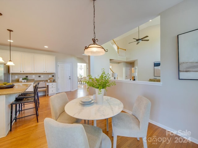 dining room featuring ceiling fan, high vaulted ceiling, and light hardwood / wood-style flooring