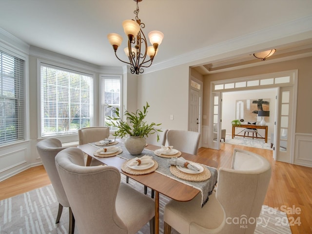 dining area featuring light hardwood / wood-style flooring, ornamental molding, and a chandelier