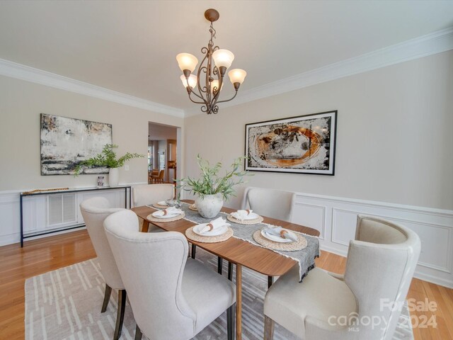 dining room featuring crown molding, a notable chandelier, and light wood-type flooring