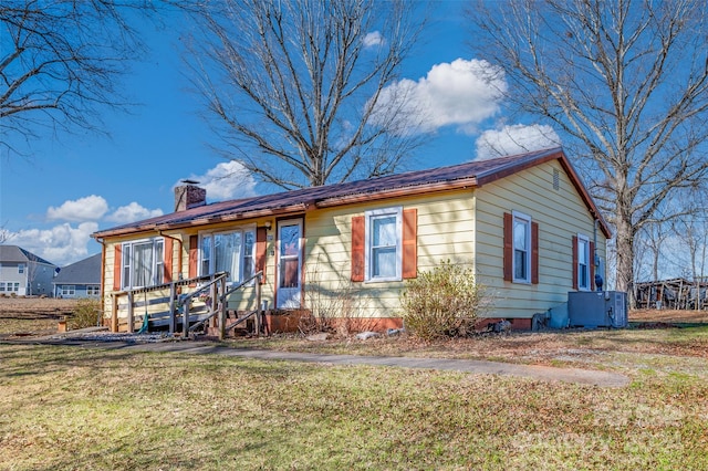 view of front of home with cooling unit and a front yard