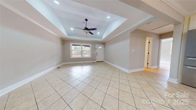 tiled empty room featuring a tray ceiling, ceiling fan, and crown molding