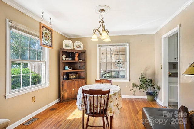 dining room featuring crown molding, hardwood / wood-style floors, a chandelier, and plenty of natural light