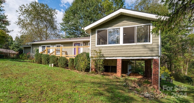 rear view of house featuring a yard and a wooden deck