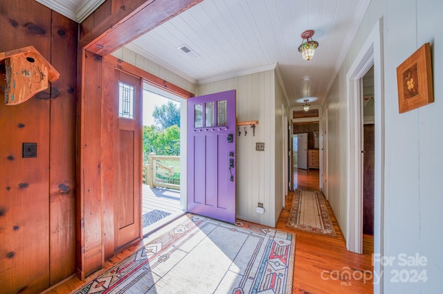 entrance foyer featuring light hardwood / wood-style flooring, wood walls, and ornamental molding