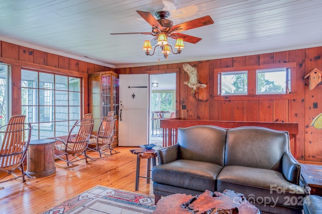 living room featuring plenty of natural light, crown molding, light hardwood / wood-style flooring, and wooden walls