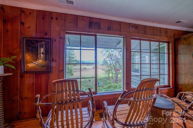 sitting room featuring wood walls, wood-type flooring, and ornamental molding