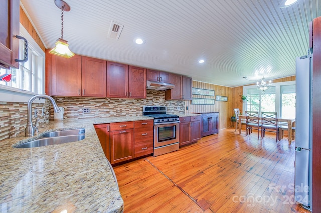 kitchen featuring appliances with stainless steel finishes, light wood-type flooring, decorative light fixtures, and sink