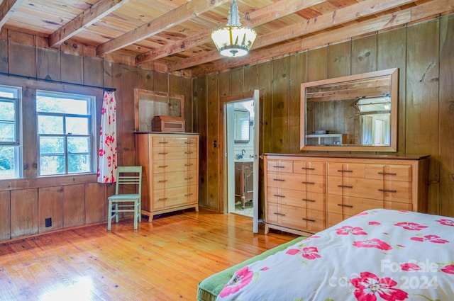 bedroom featuring beamed ceiling, wood walls, hardwood / wood-style floors, wooden ceiling, and ensuite bathroom