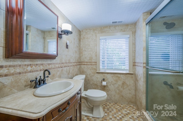 bathroom with vanity, tile walls, a shower with shower door, and toilet