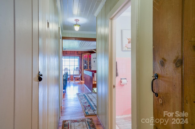 hall featuring ornamental molding, wooden walls, tile walls, and hardwood / wood-style floors