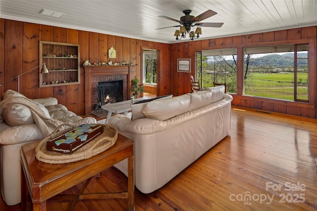 139 Neely Rd, Brevard, NC 28712 - living room with wood walls, a ceiling fan, a brick fireplace, and visible vents