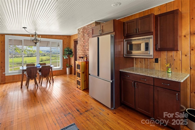 139 Neely Rd, Brevard, NC 28712 - kitchen featuring a chandelier, light wood finished floors, wood walls, appliances with stainless steel finishes, and light stone countertops